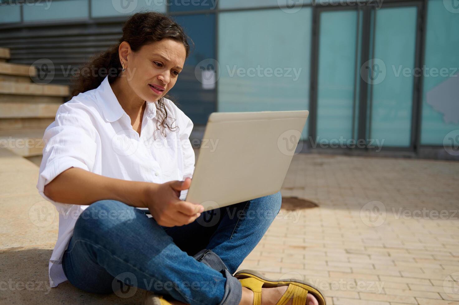 Portrait of multitasking businesswoman expressing difficulties, thinking on business development strategy, using laptop photo