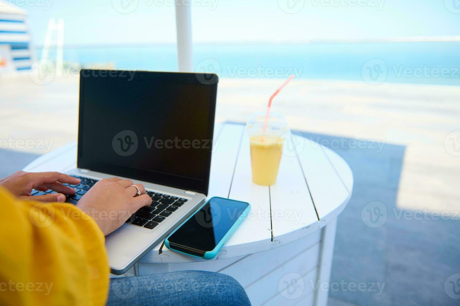 Rear view of a laptop with blank black mockup screen and businesswoman typing text on keyboard. Copy advertising space photo