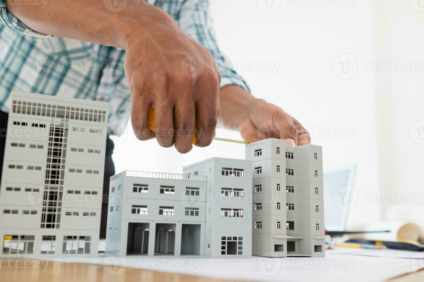 architect is preparing house model and construction plans on blueprints for construction engineering team to review before construction engineering team constructs building according to the drawings. photo