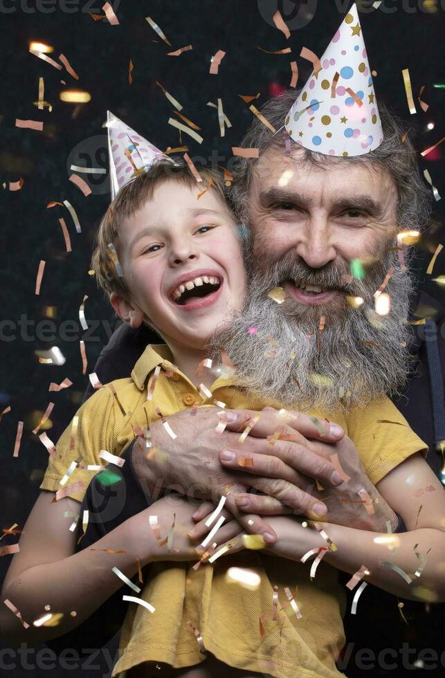 Portrait of a happy grandfather with a beard and grandson of the birthday boy on a black background. photo