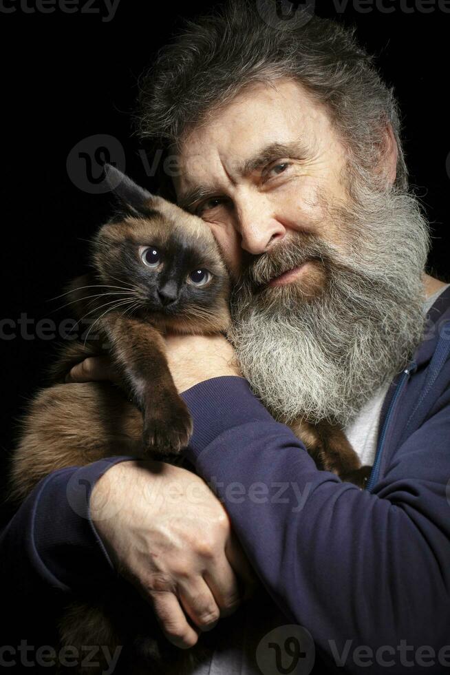 Portrait of an elderly man with a gray beard holding a cat. Man and pet. photo