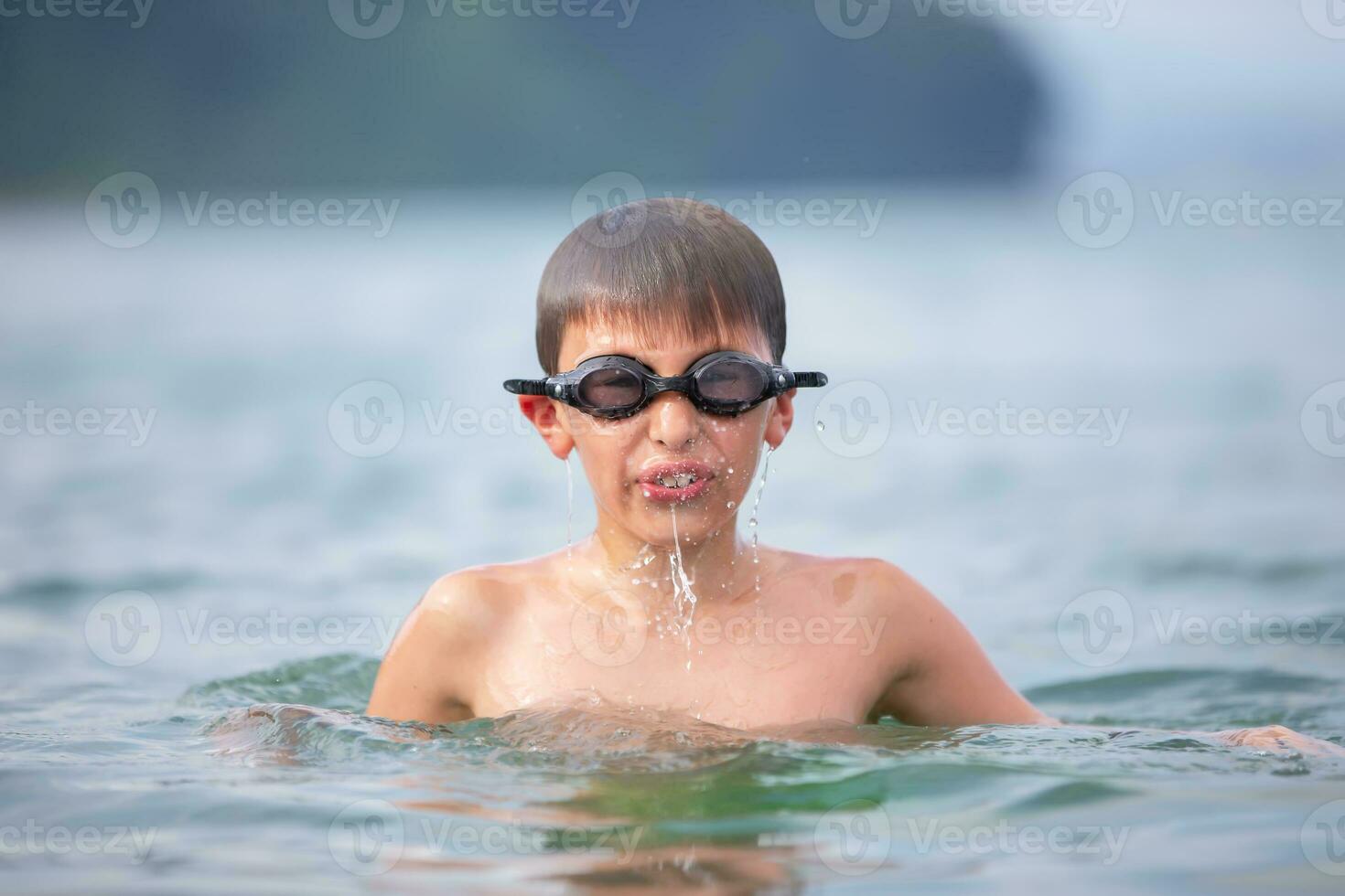 A boy in swimming goggles swims in the sea. photo