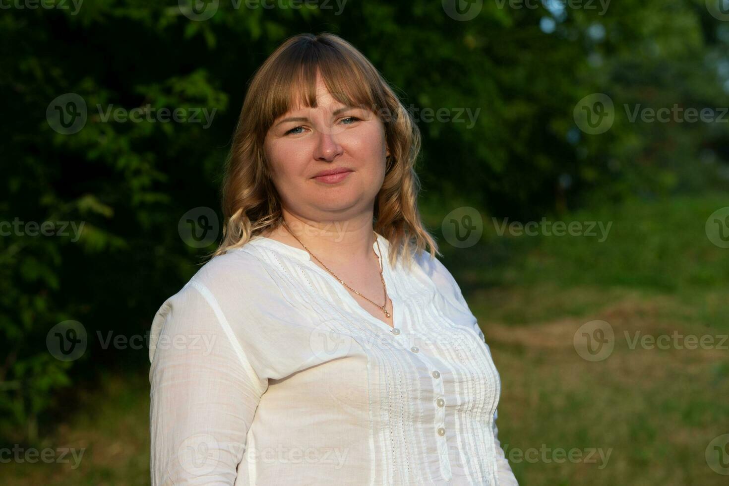 A plump blonde with blue eyes looks into the camera. photo