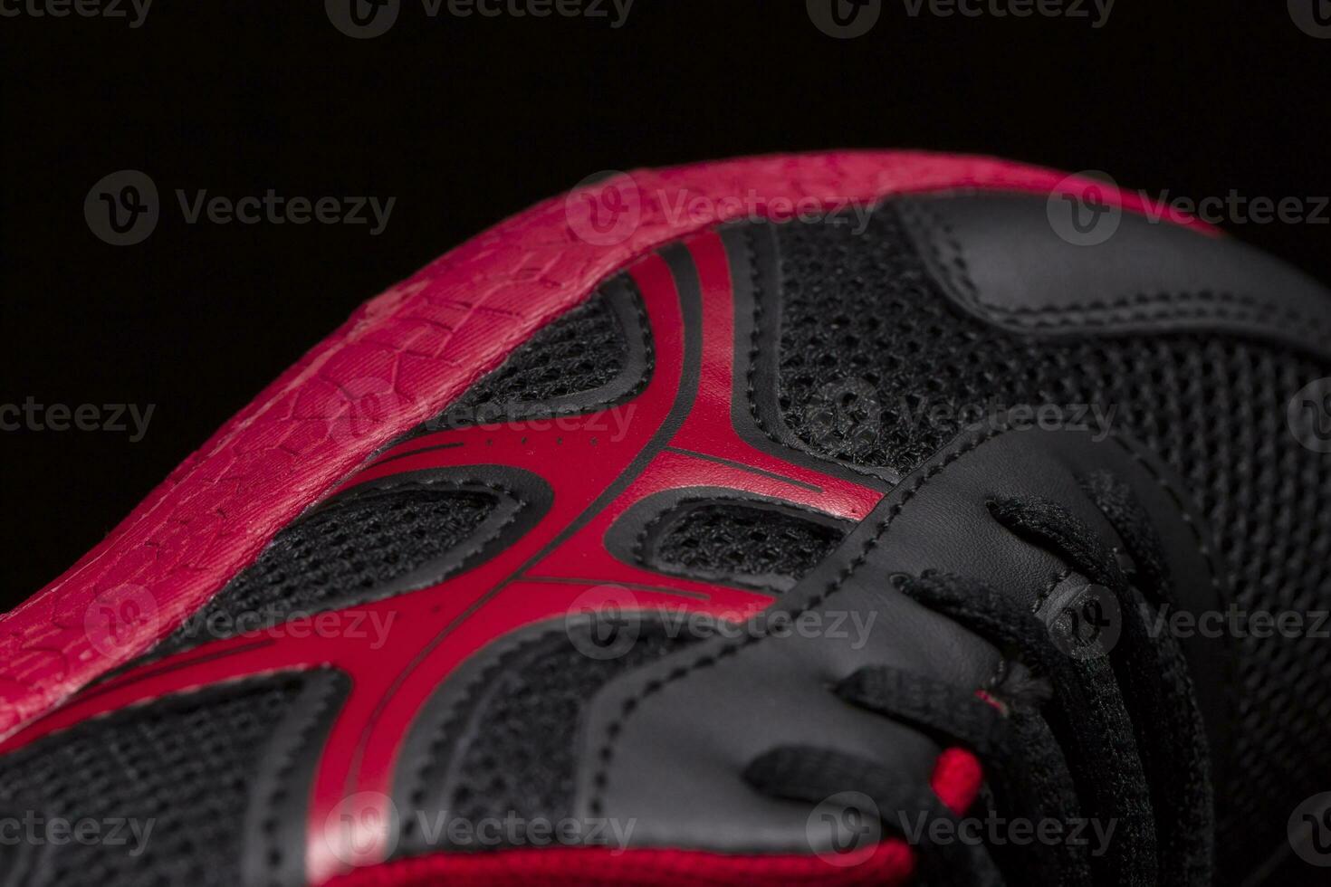 A fragment of a black sneaker with a red sole close up. Sneaker texture photo