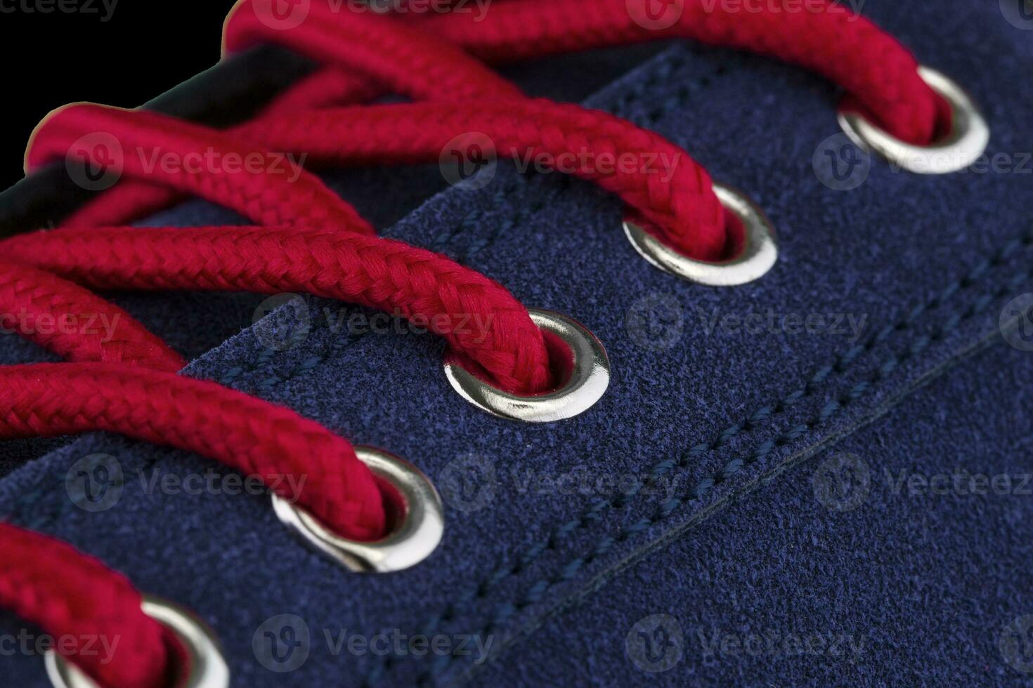 A fragment of a blue sneaker with red laces close up. Sneaker texture photo