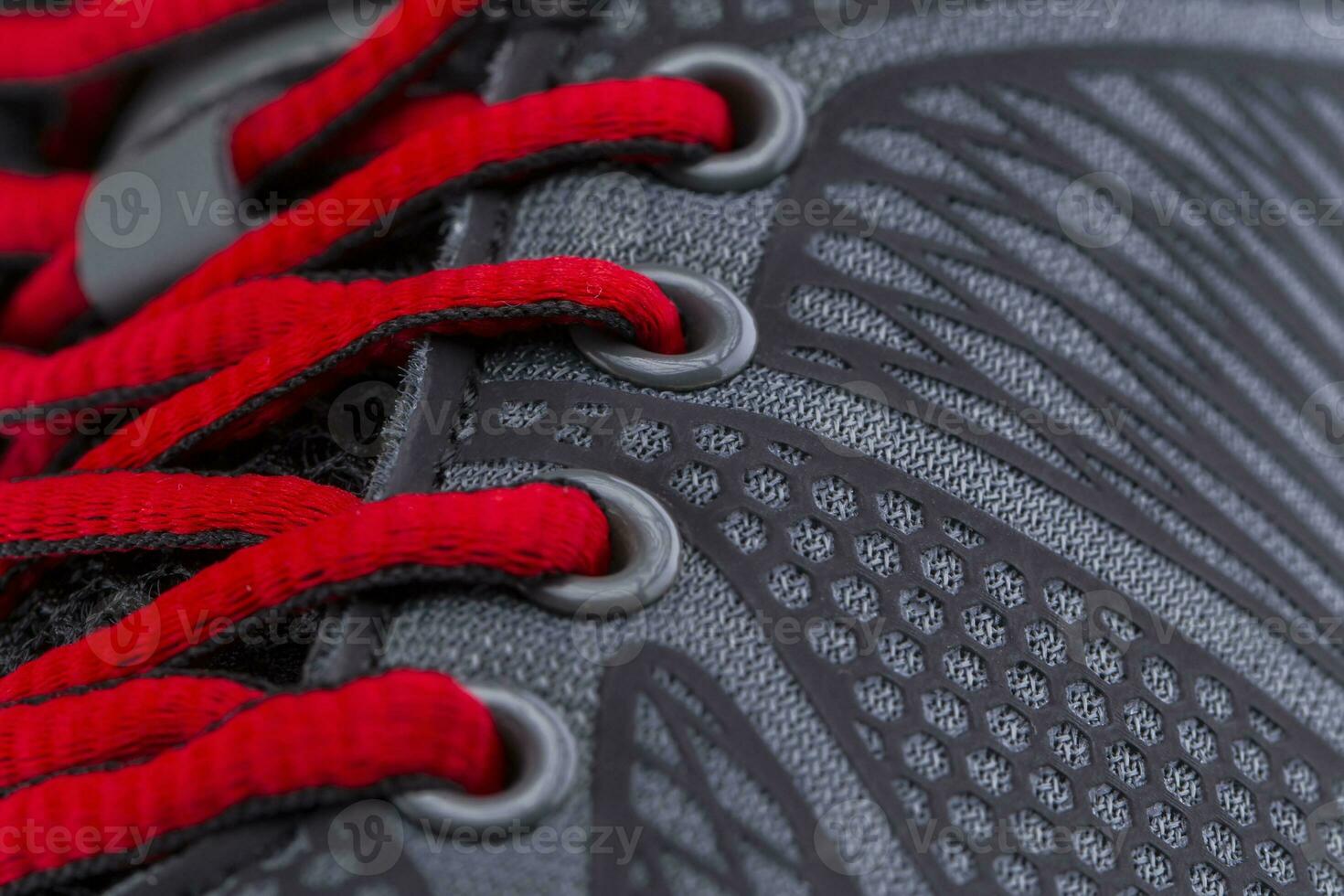 A fragment of a black sneaker with red laces close up. Sneaker texture photo