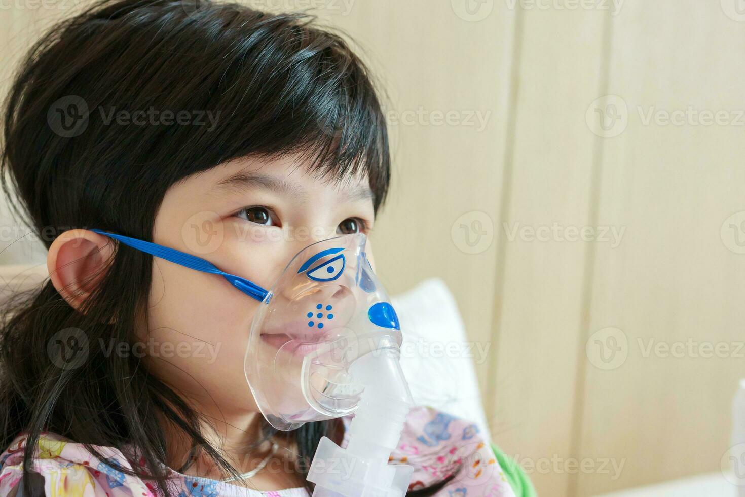 Sick little asian girl inhalation with nebulizer for respiratory treatment photo