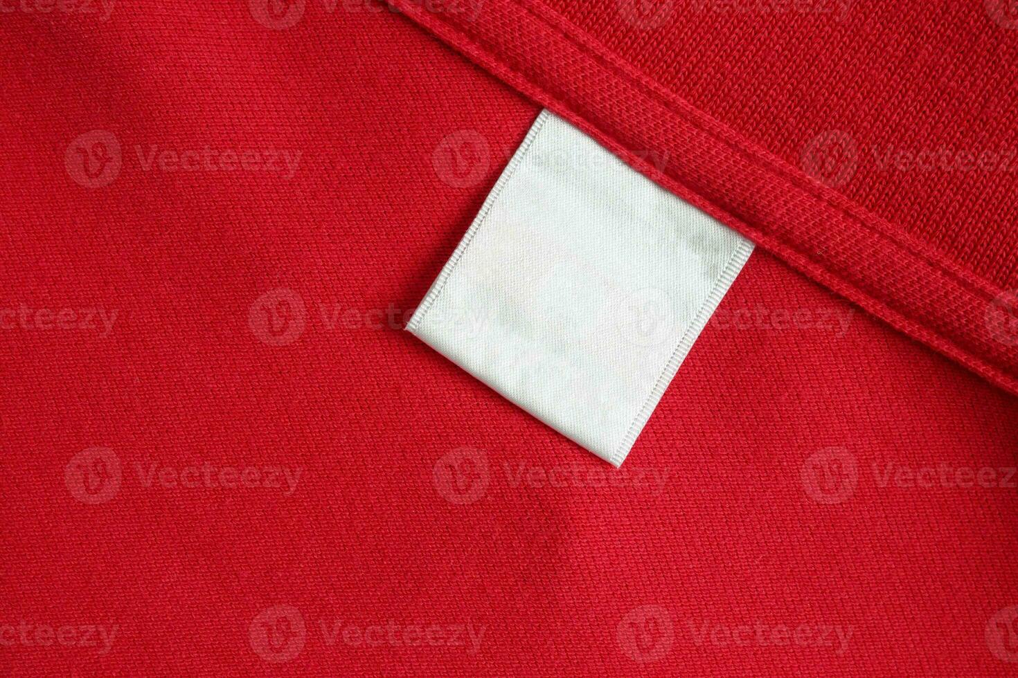 Blank white laundry care clothes label on red shirt fabric texture background photo