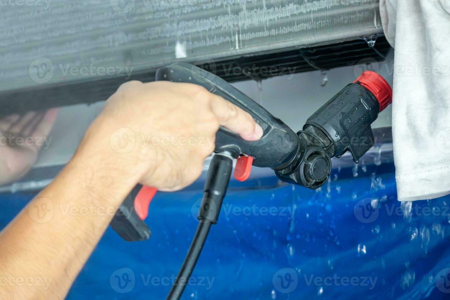 Servicio de limpieza de aire acondicionado con spray de agua. foto