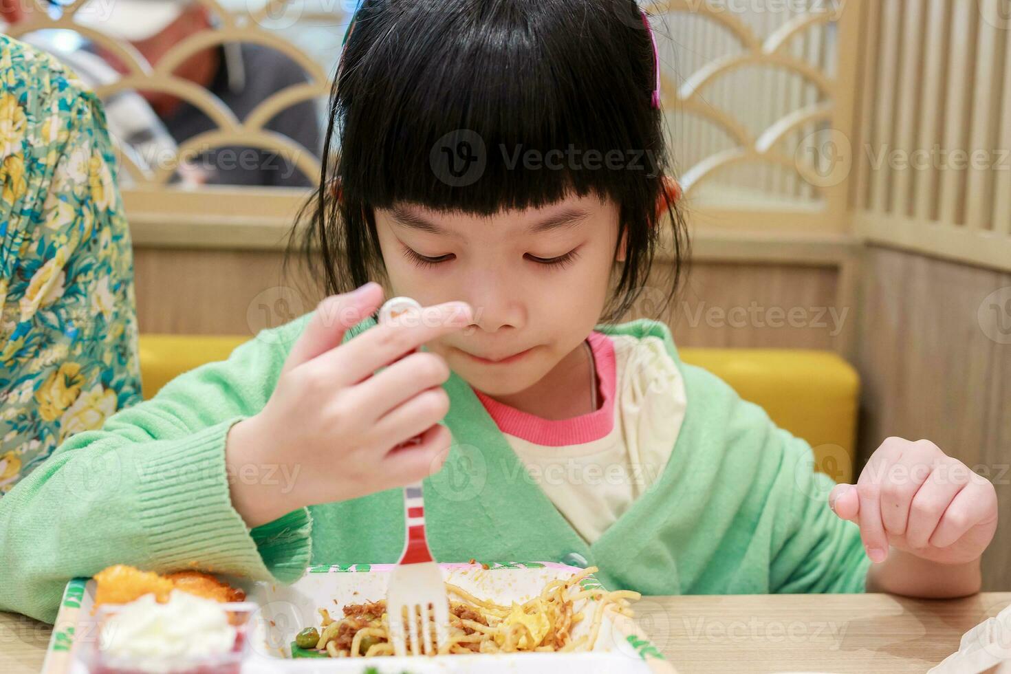 linda pequeño asiático niño niña comiendo comida foto