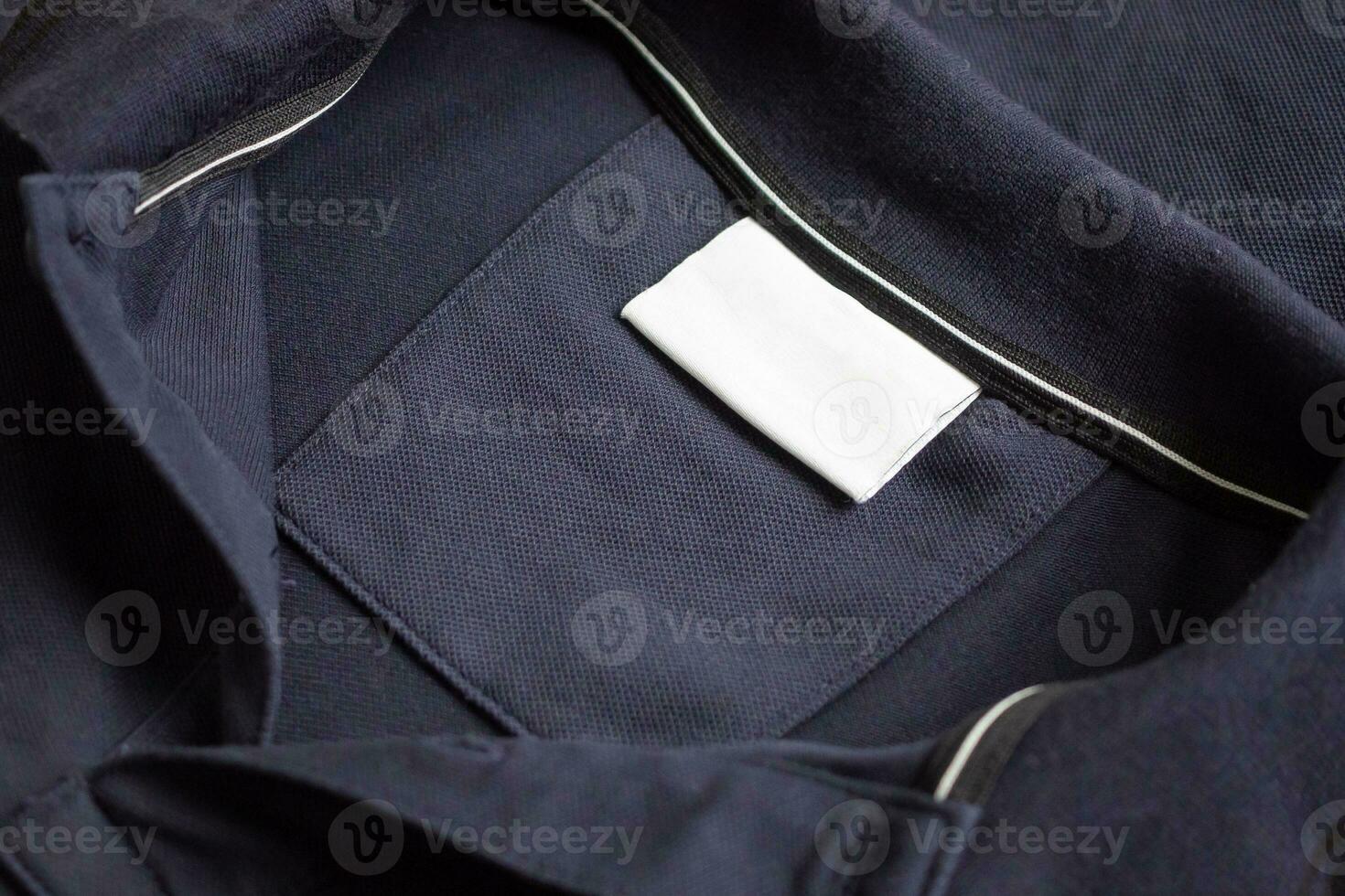 Blank white laundry care clothes label on black shirt fabric texture background photo