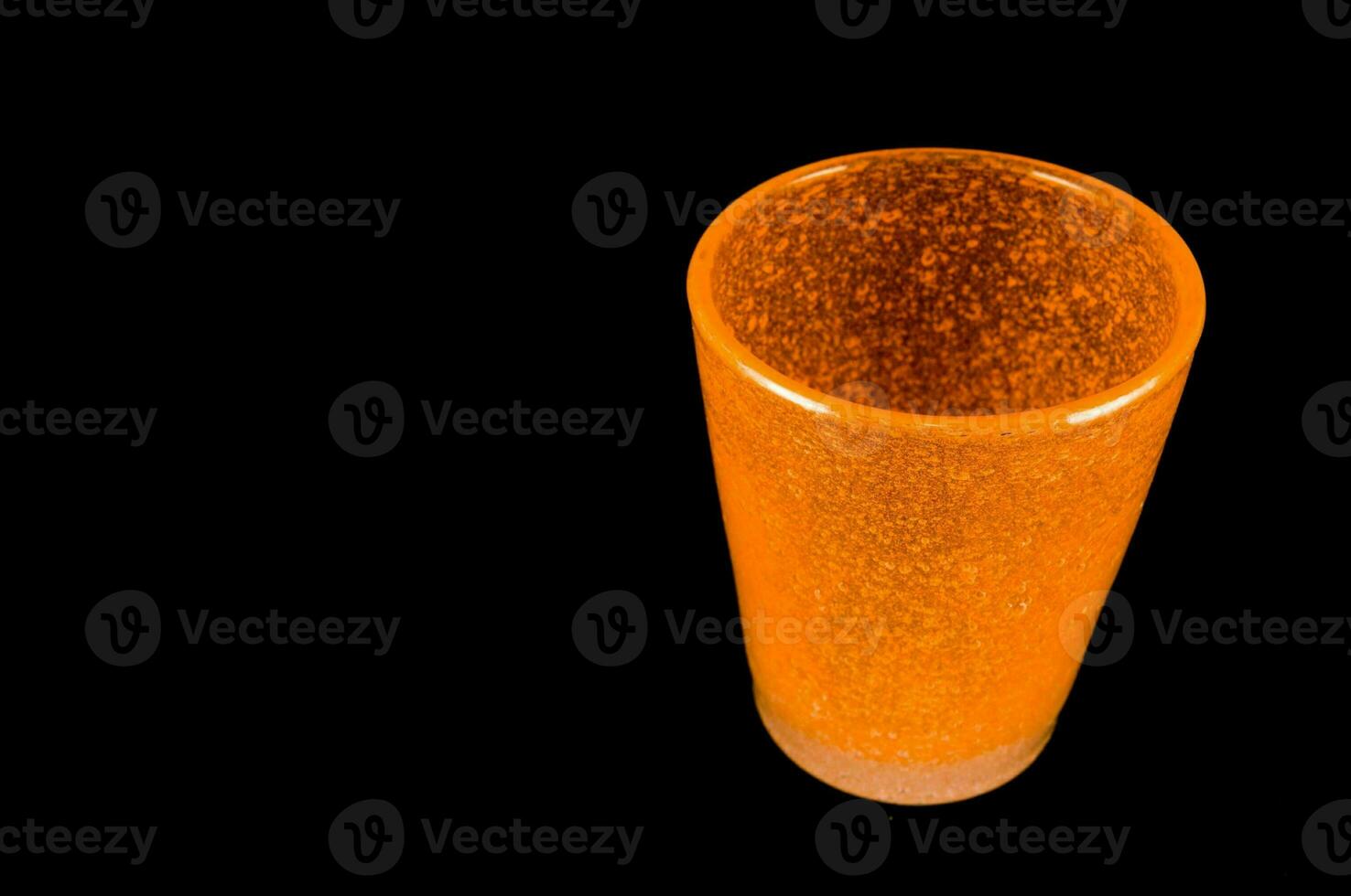 a glass of orange liquid sitting on a black surface photo