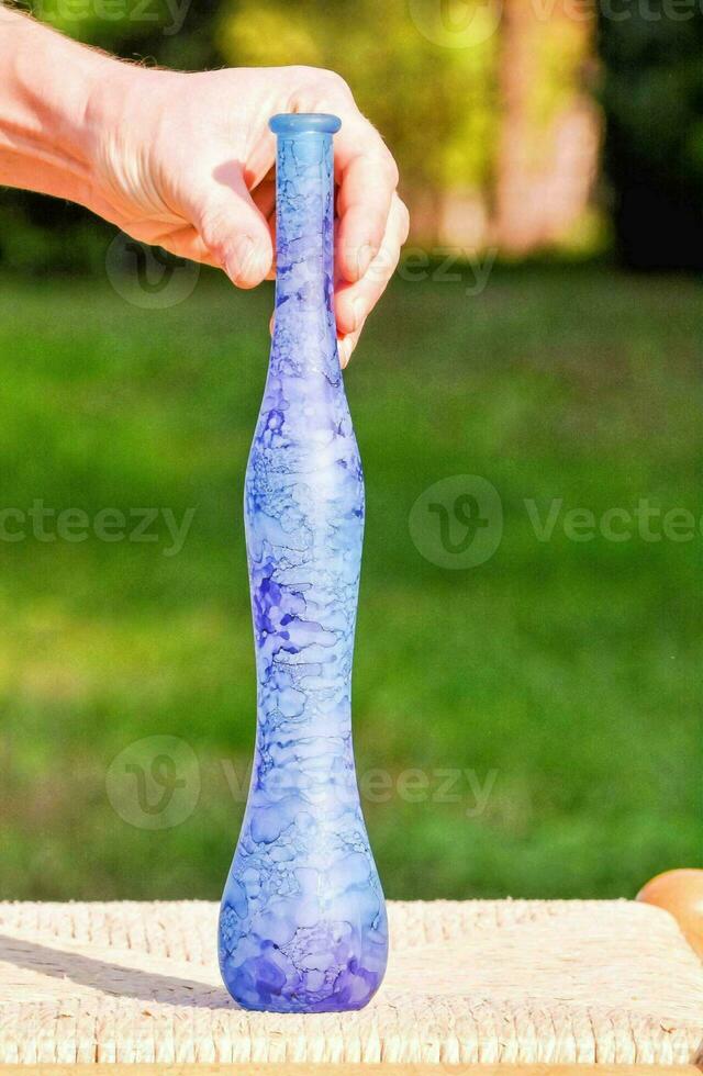 a person holding a blue bottle with a wooden handle photo