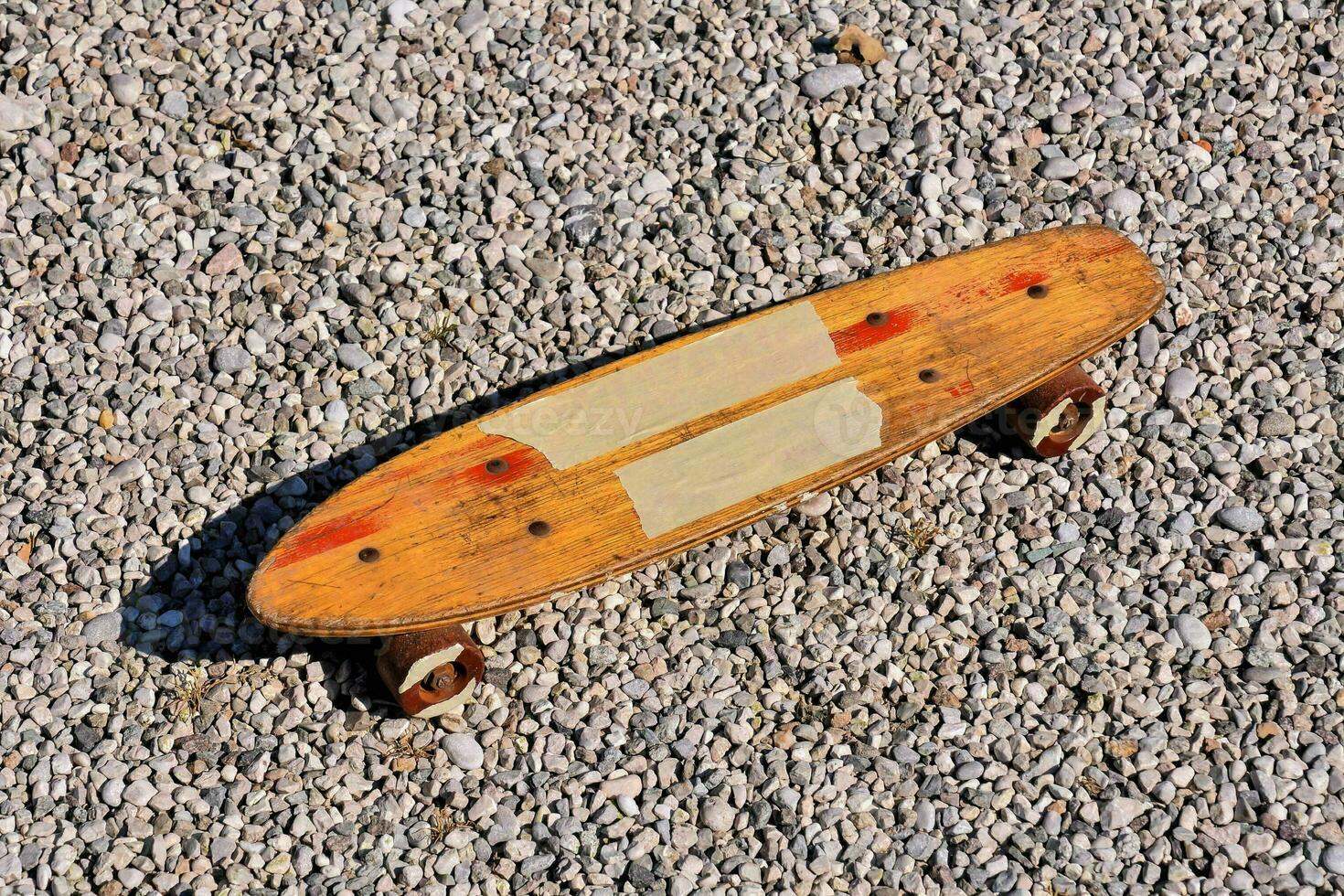 a wooden skateboard laying on gravel photo