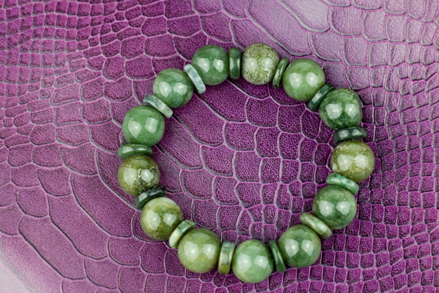Green jade bracelet on a purple leather background. Close up. photo