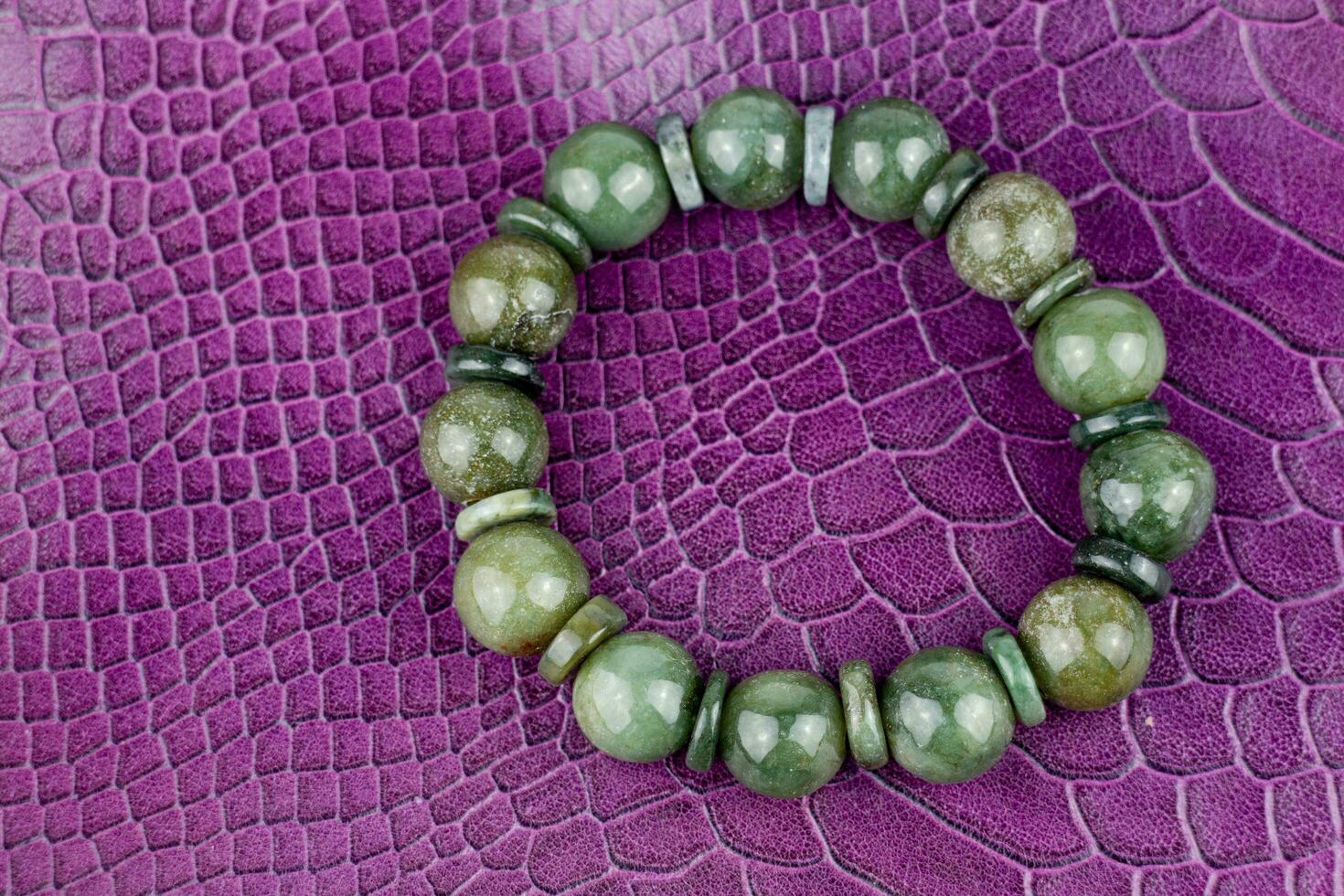 verde jade pulsera en un púrpura cuero antecedentes. cerca arriba. foto