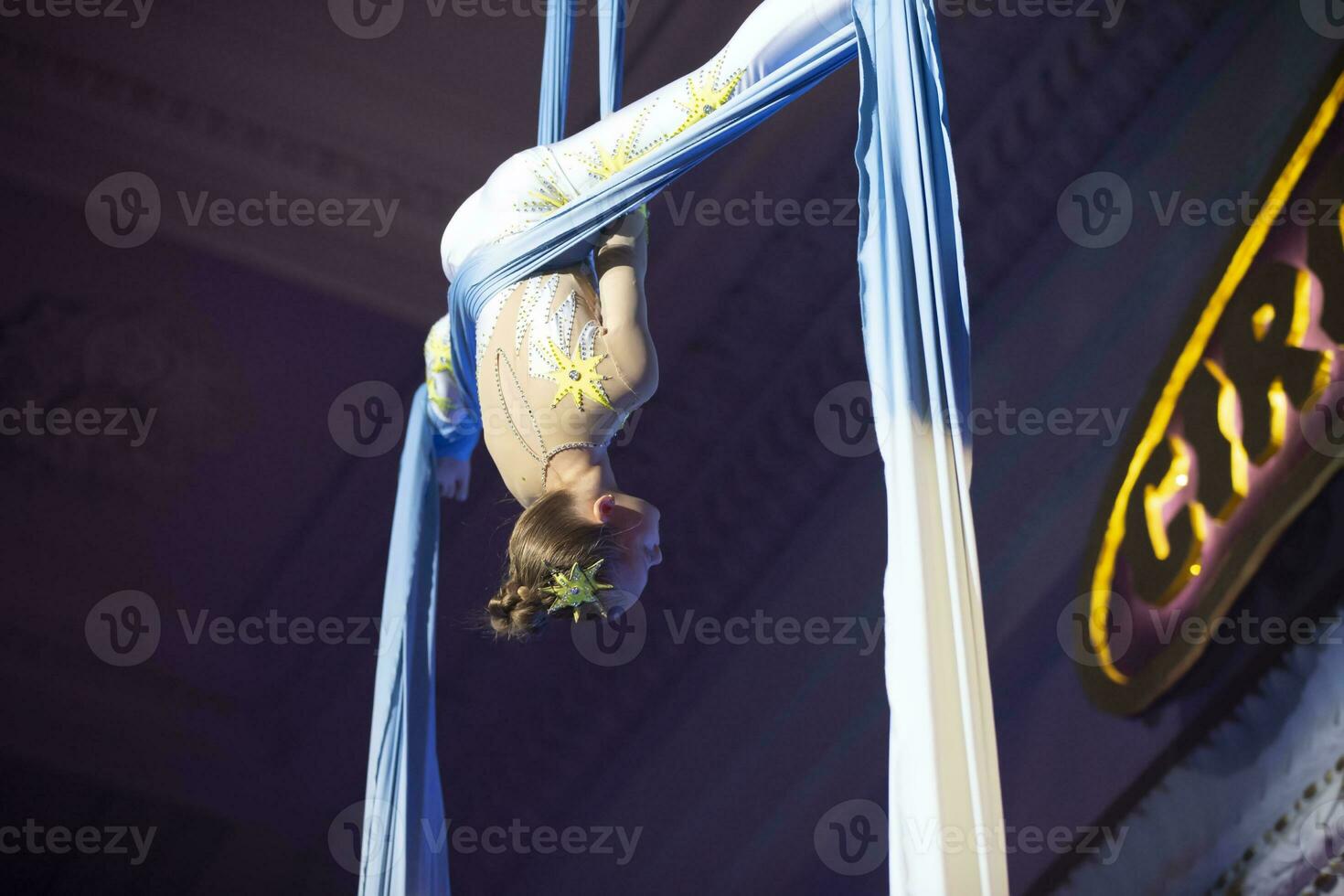 The girl performs acrobatic numbers on the canvases. A small circus artist performs on the canvases of acrobats. Child perform acrobatic elements in the air photo