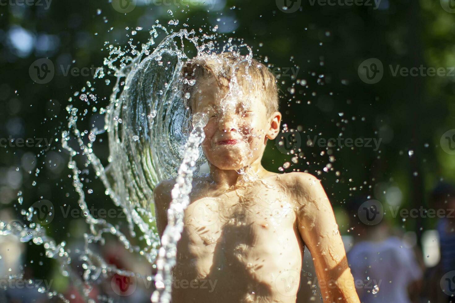 A little boy enjoys the cold waters of a fountain during the heat wave. Conceptual photography of hot weather, heat wave, global warming, summer season, climate change, enjoy life. photo