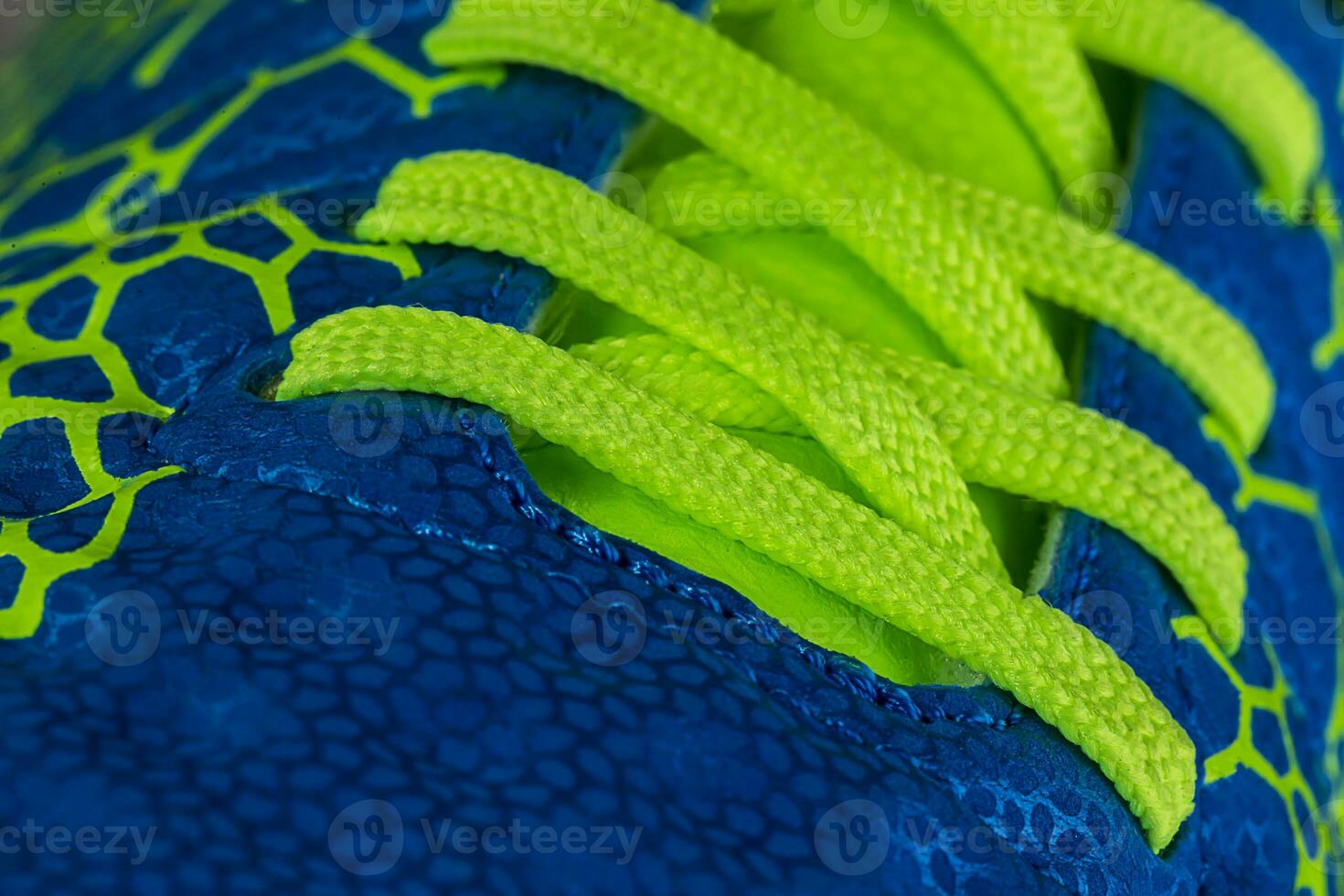 Fragment of a blue sneaker with green laces close up. Sneaker texture photo