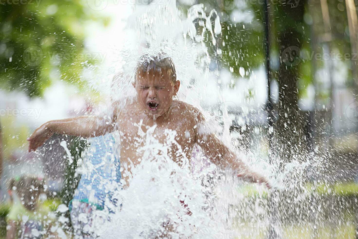 A little boy enjoys the cold waters of a fountain during the heat wave. Conceptual photography of hot weather, heat wave, global warming, summer season, climate change, enjoy life. photo