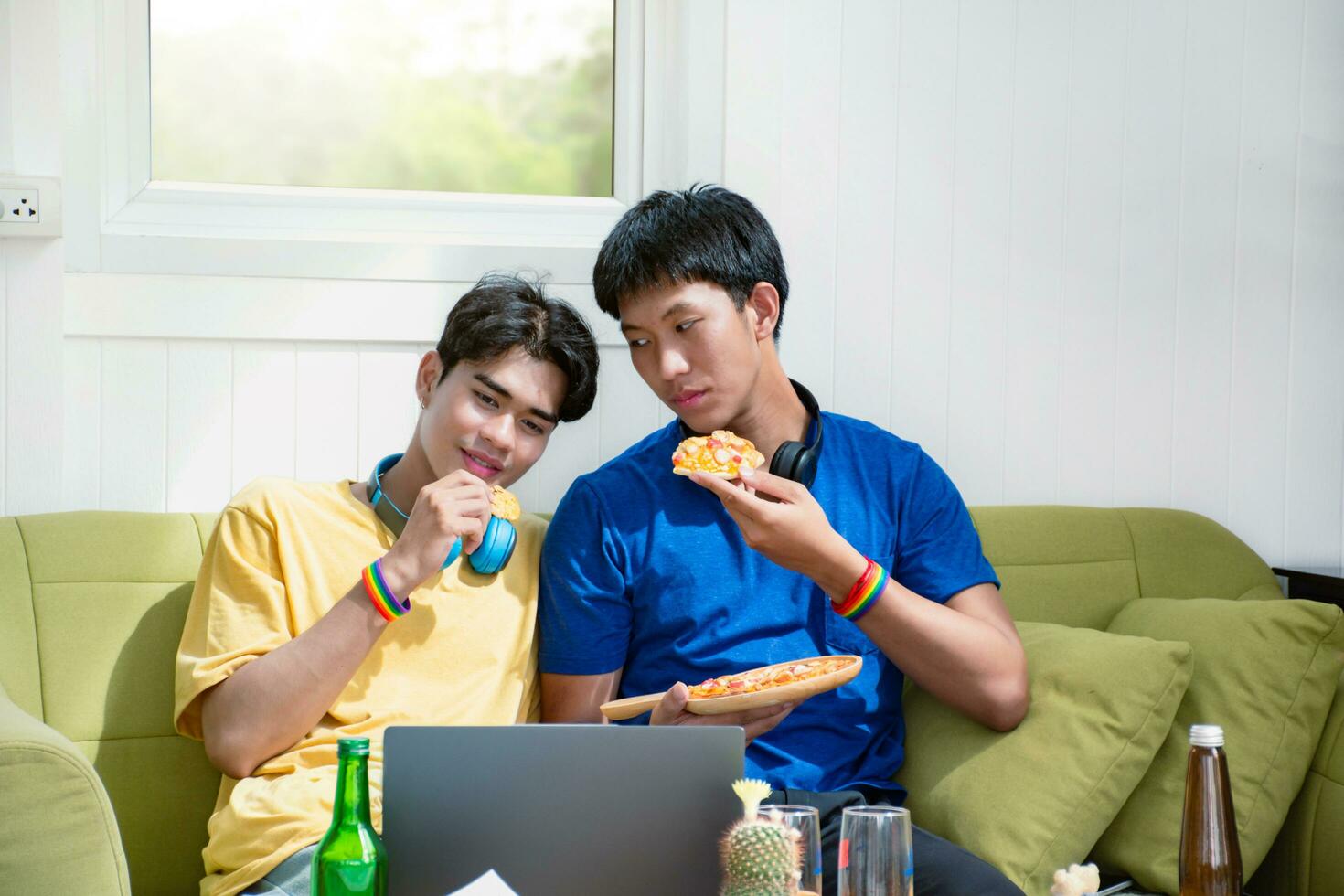 Portrait of two young asian gay couples sitting on sofa, spending their free time and watching tv at home together, concept for lifestyle of LGBT people around the world. photo