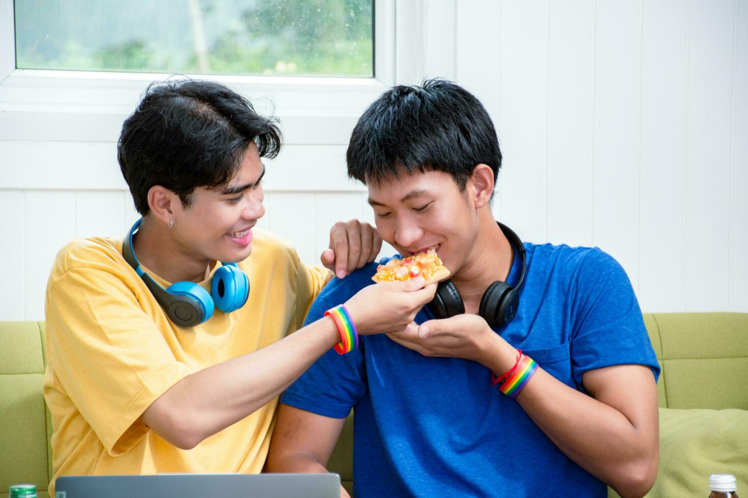 retrato de dos joven asiático gay parejas sentado en sofá, gasto su gratis hora y acecho televisión a hogar juntos, concepto para estilo de vida de lgbt personas alrededor el mundo. foto