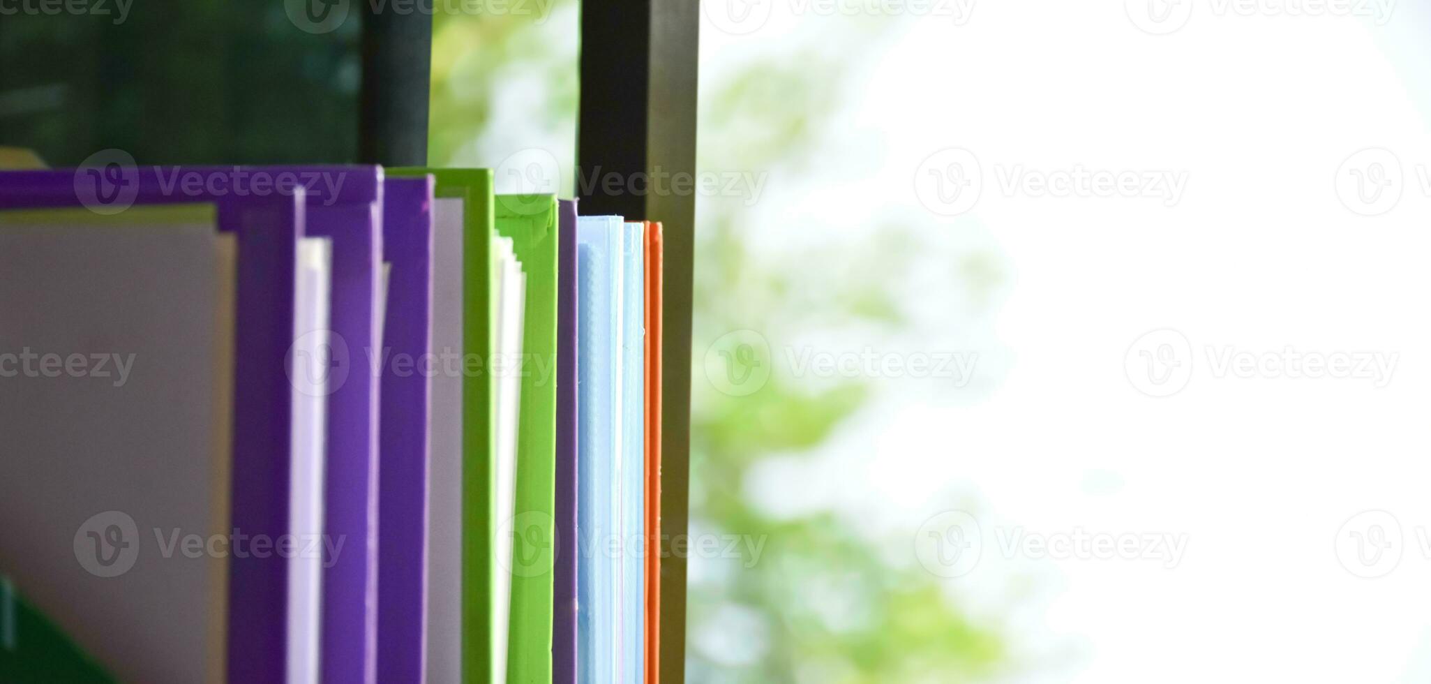 Back view of various plastic file folders for storing important documents in a file box for neatness and easy finding places near transparent glass window, blurred edited background. photo