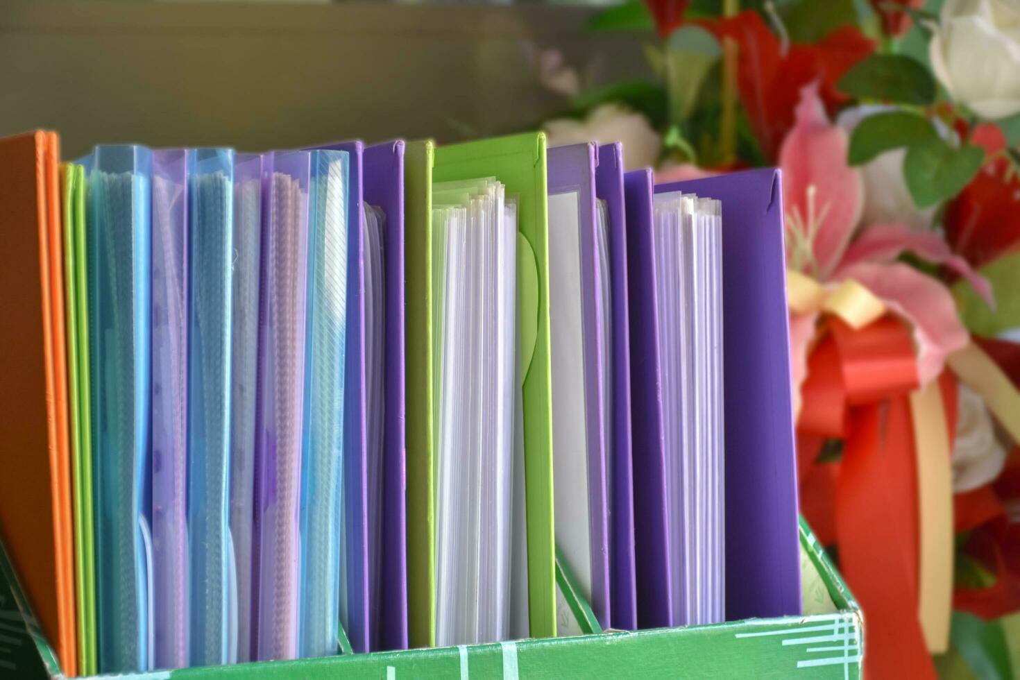 Back view of various plastic file folders for storing important documents in a file box for neatness and easy finding places near transparent glass window, blurred edited background. photo