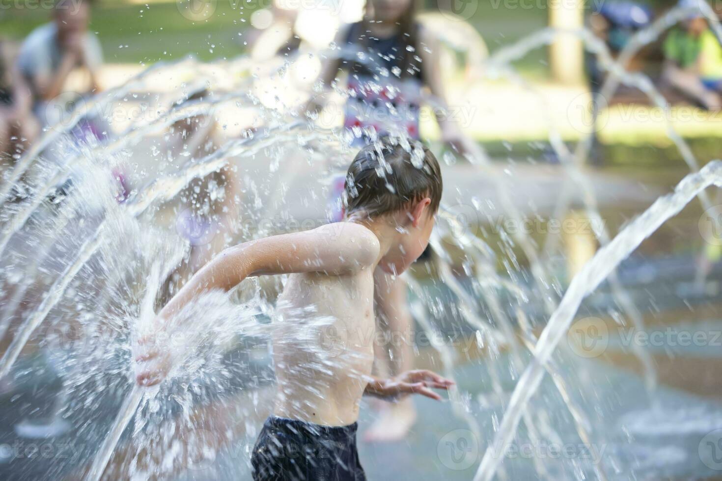 A little boy enjoys the cold waters of a fountain during the heat wave. photo