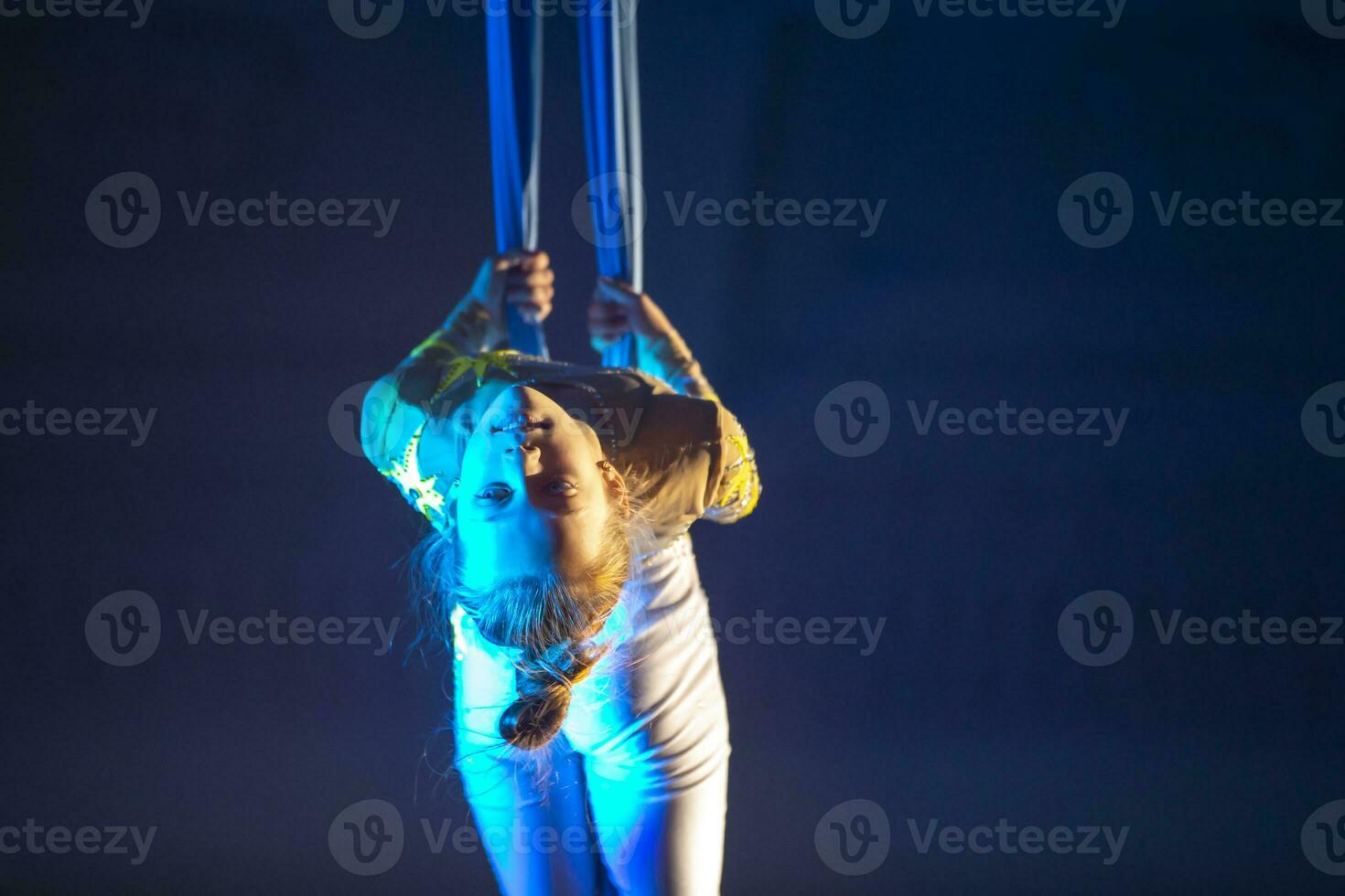 The girl performs acrobatic numbers on the canvases. A small circus artist performs on the canvases of acrobats. Child perform acrobatic elements in the air photo