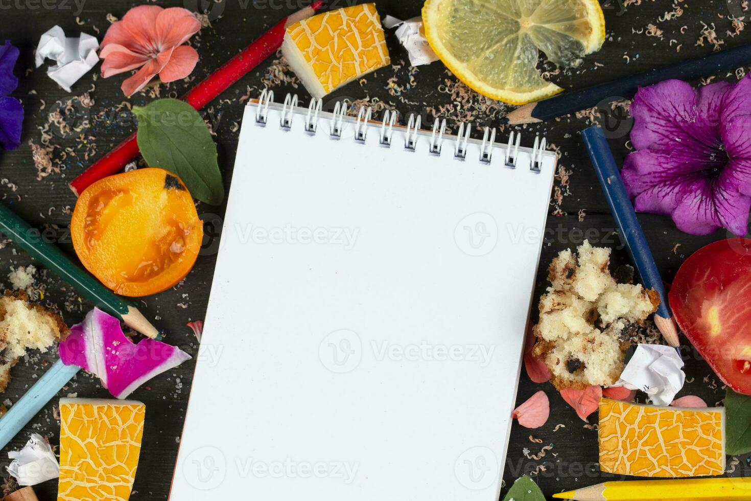 Paper notebook with blank pages, crumpled paper balls and crayons, scattered foods on wooden background, creative cooking recipe writing concept. Coming up and writing down recipes for cooking. photo