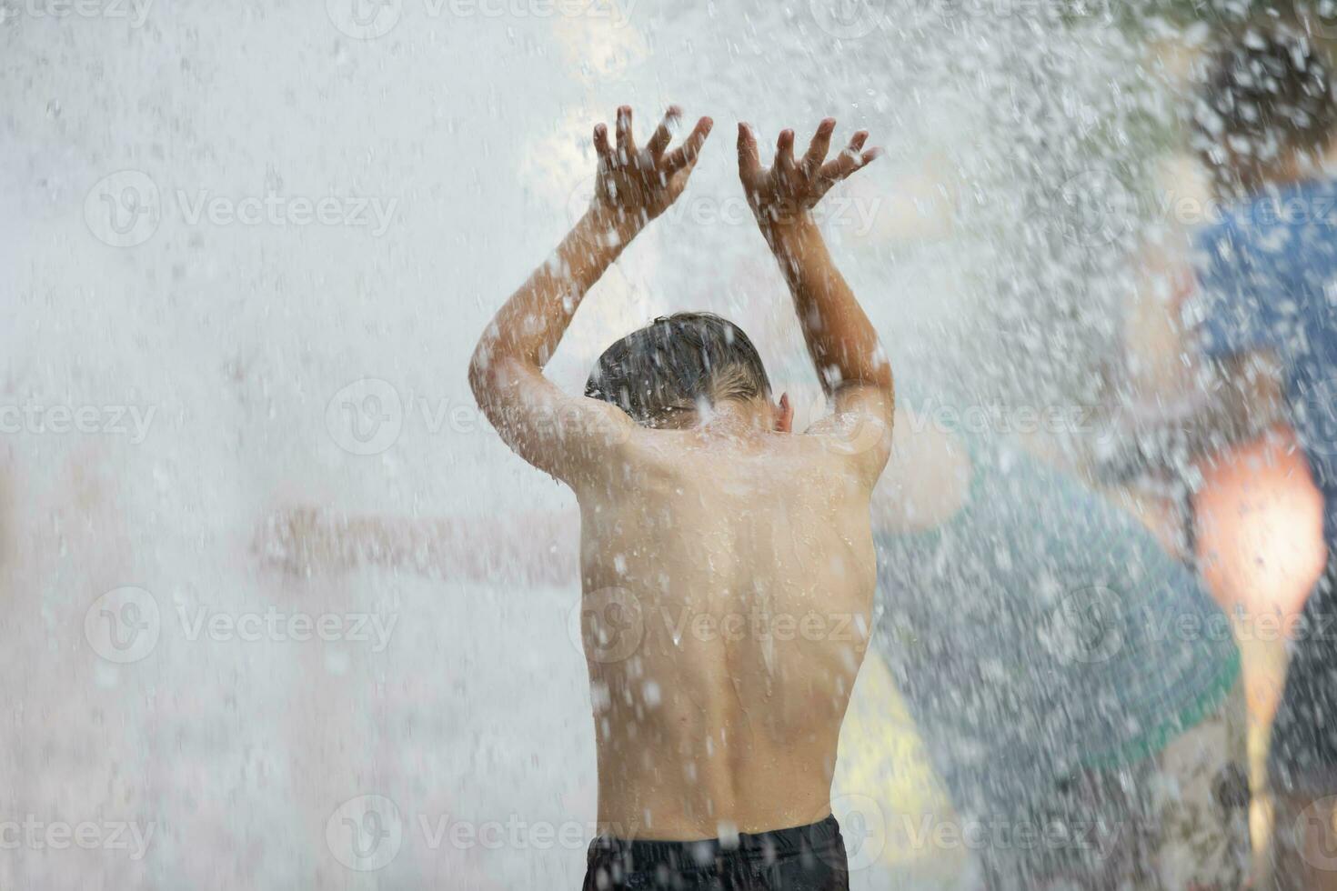 Child in the rain. A little boy stands with his back to the camera in the pouring rain. photo