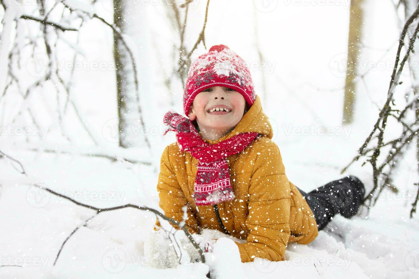 Funny little boy in colorful clothes playing outdoors during a snowfall. Active holidays with children in winter on cold snowy days. Happy child is having fun and playing in winter. photo