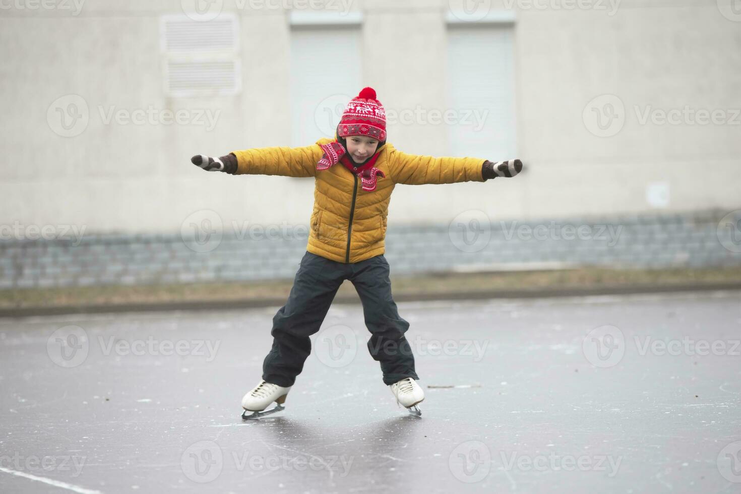 Little boy in winter clothes learns to skate.A child on an ice rink. photo