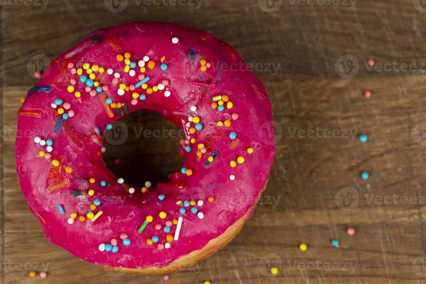 Creative sweet food. Glazed colorful donut on a wooden background. photo