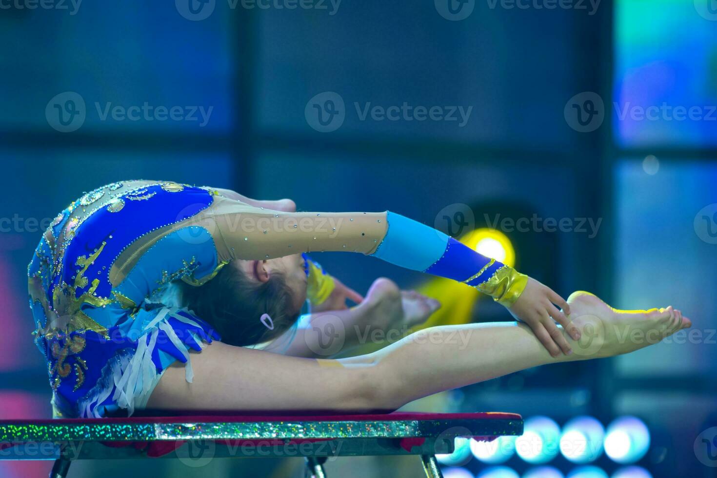 Plastic little girl gymnast. A child with a flexible body performs on stage. photo