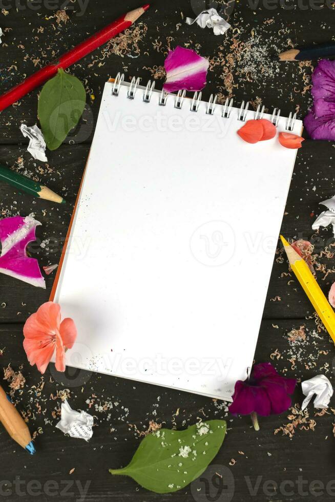 Paper notebook with blank pages, crumpled paper balls and colored pencils on wooden background, creative writing concept. A minimalist workplace for a writer or artist. Creative torment. photo