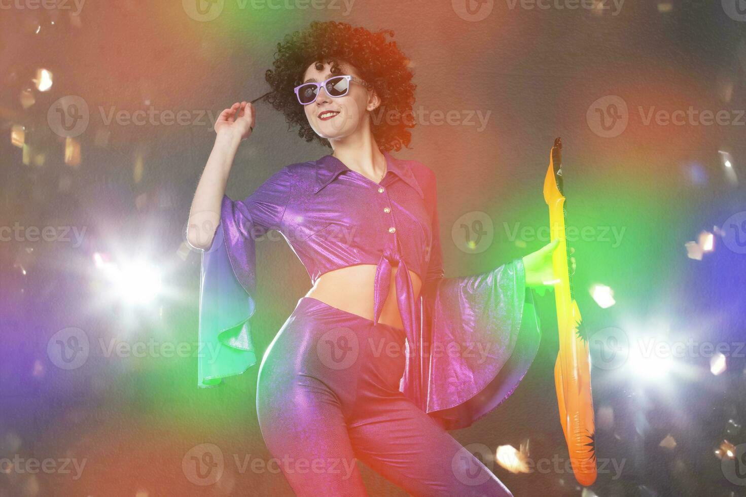 Happy girl pop singer with a toy guitar on the background of shiny confetti. Disco style. photo