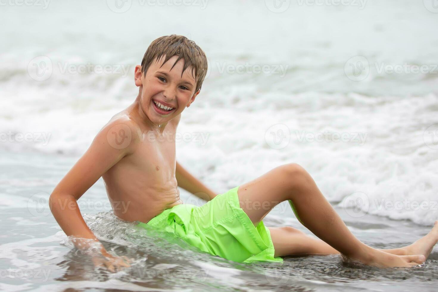 Happy boy swims at the sea, looks into the camera. Summer rest. photo