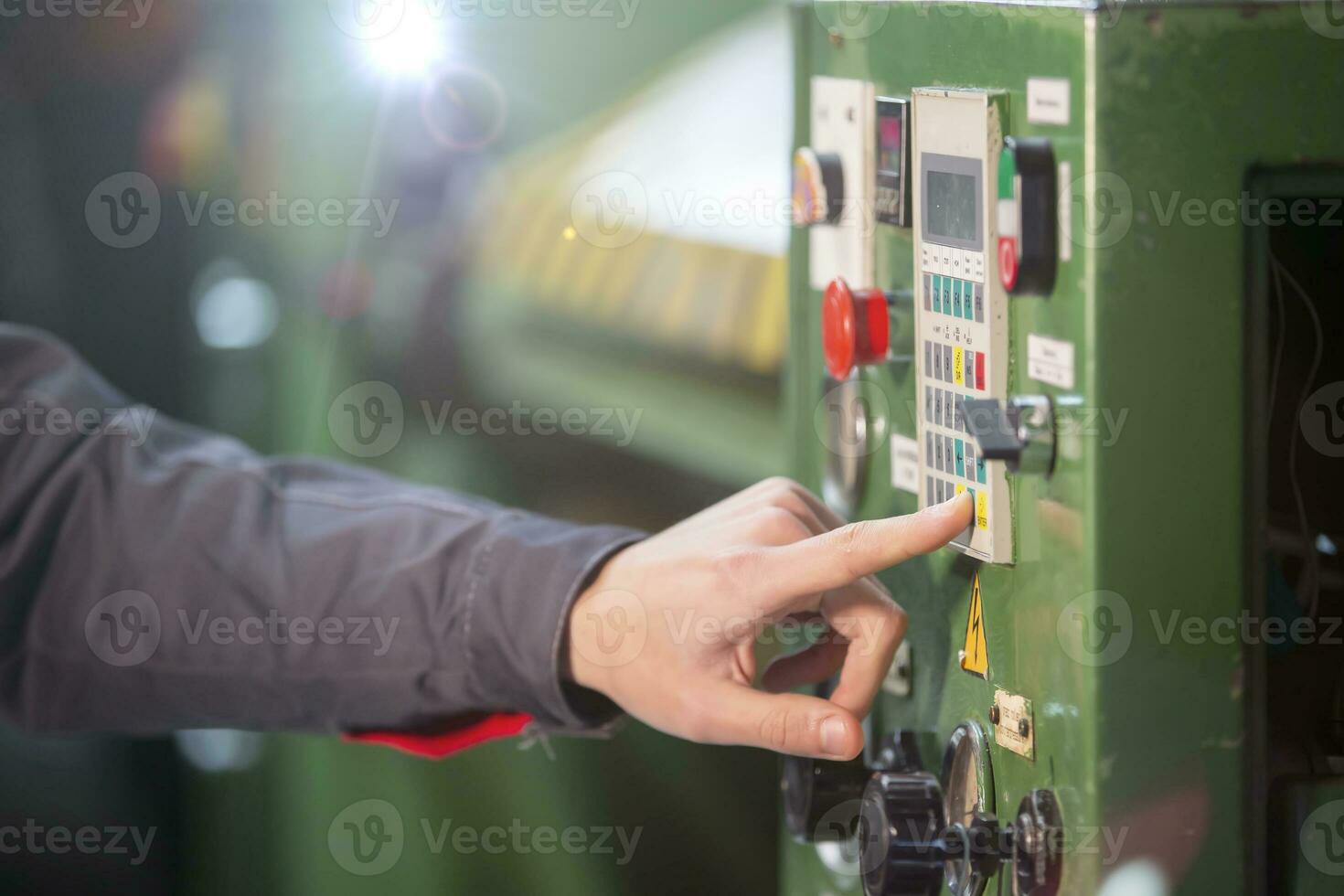 A worker's hand presses a button on a CNC machine. photo