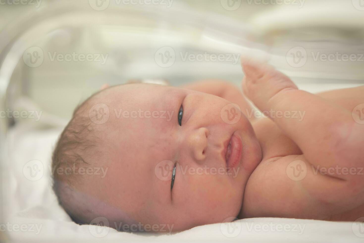 A newborn baby lies in a special medical box. photo