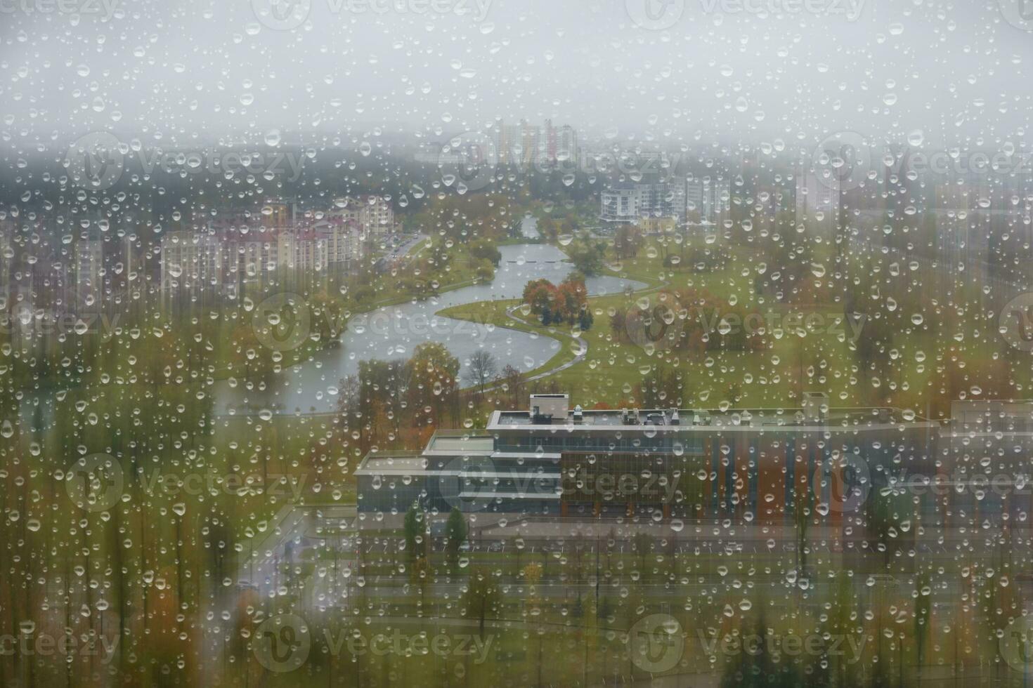 Behind the glass covered with autumn raindrops is a landscape of a gray and boring city. photo