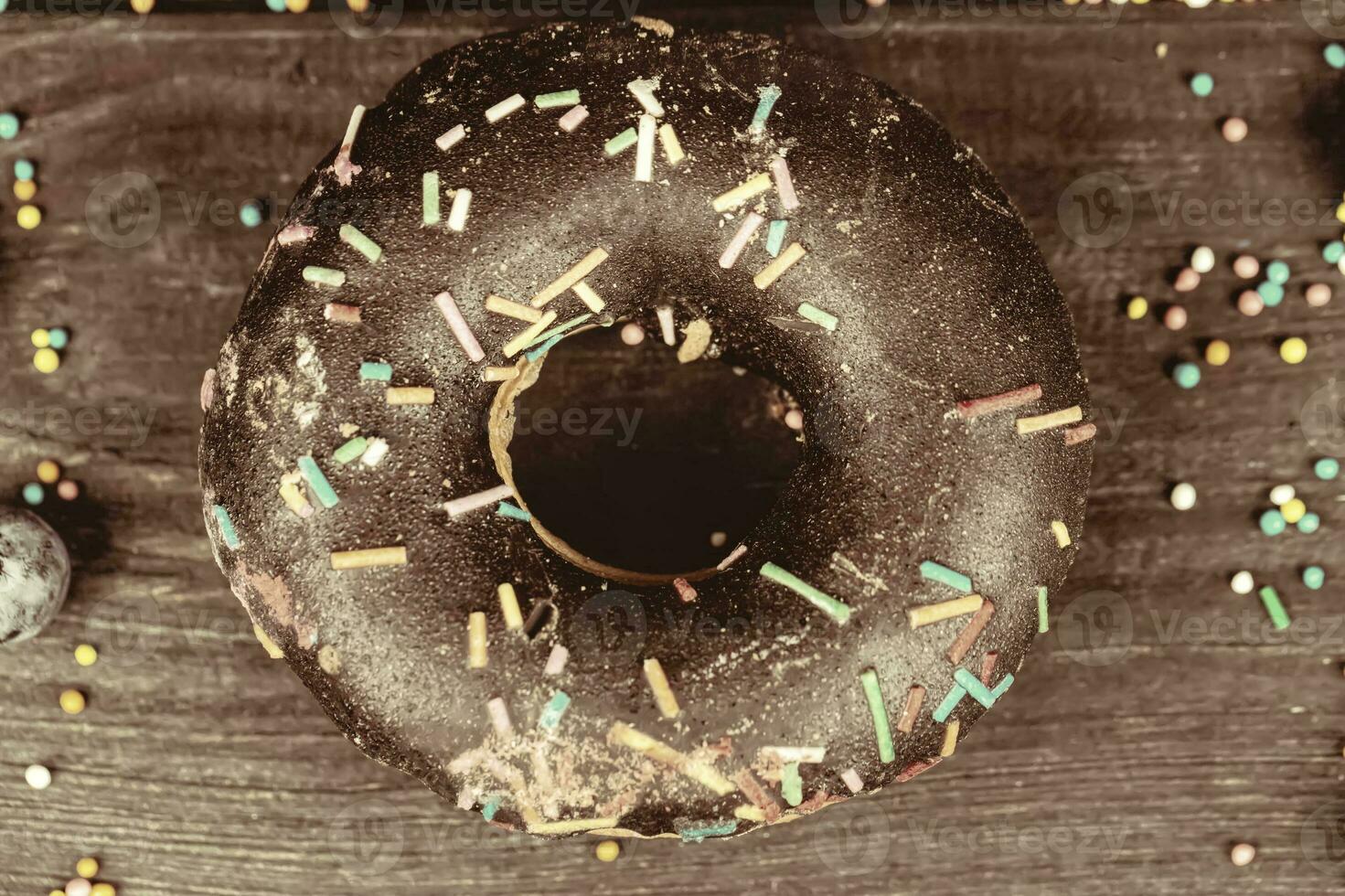 Creative sweet food. Donut of beige solid color on a wooden background. photo