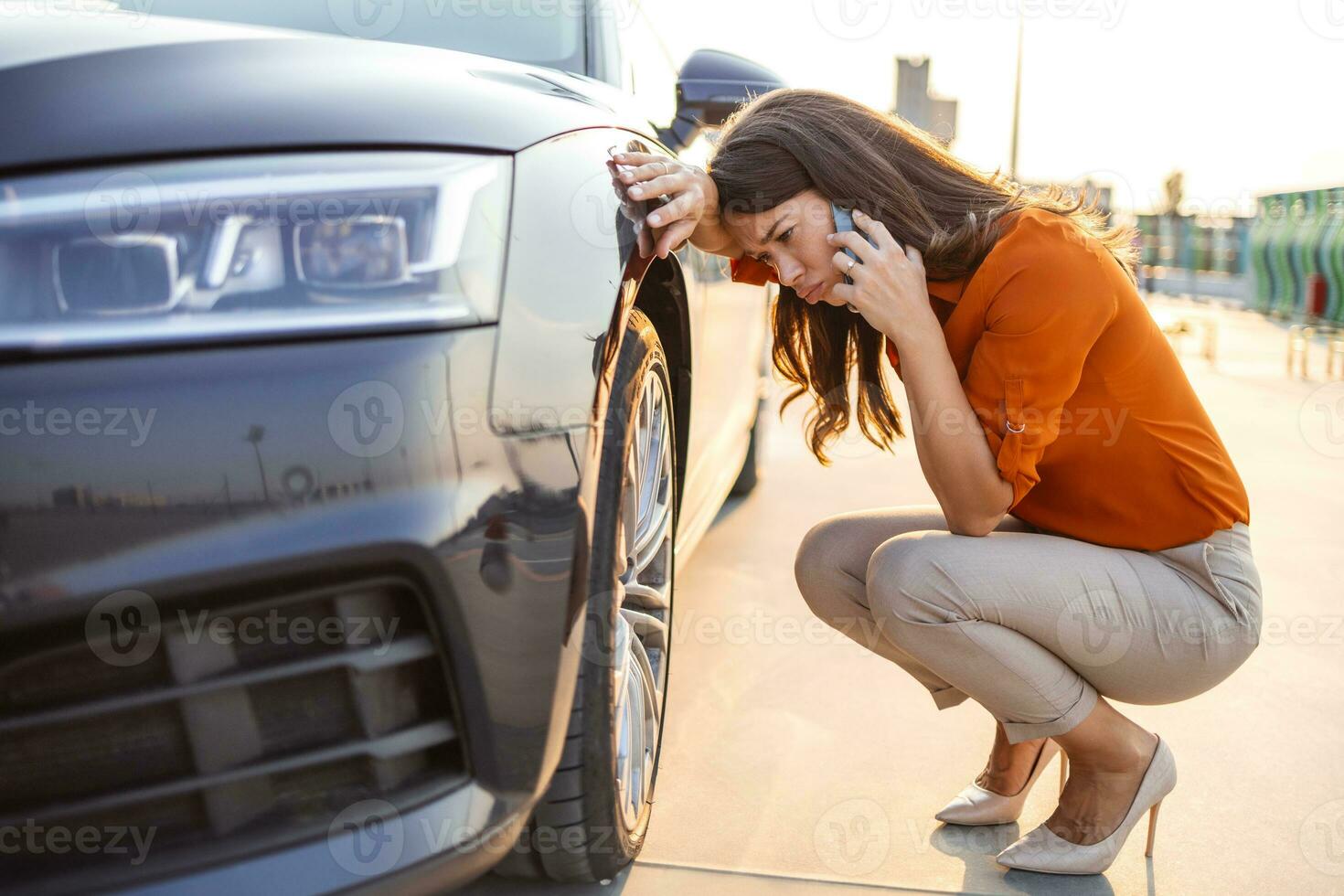 Sad woman sits at the punctured wheel of a car. Tire service and car service on call. Courses for drivers and car mechanics. Pump for car wheels. Solar glare photo