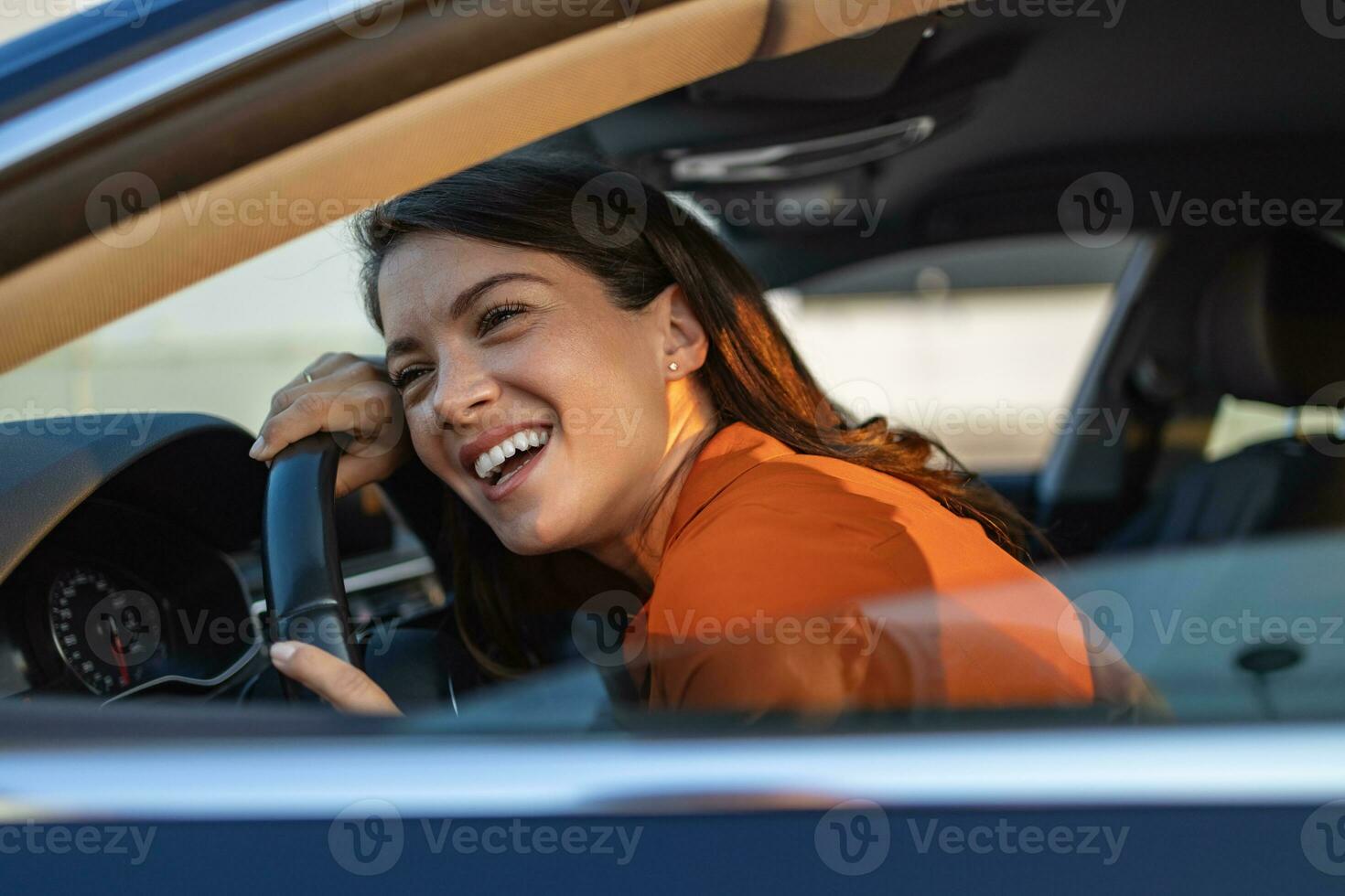 Young Woman Embracing Her New Car. Excited young woman and her new car indoors. Young and cheerful woman enjoying new car hugging steering wheel sitting inside photo