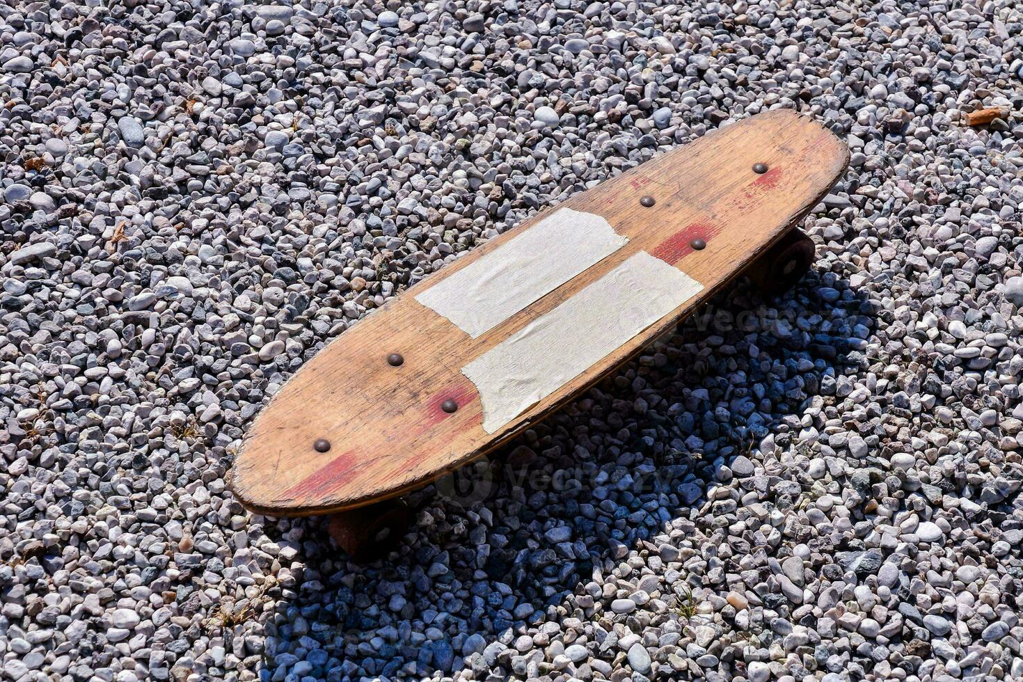 a wooden skateboard on gravel photo