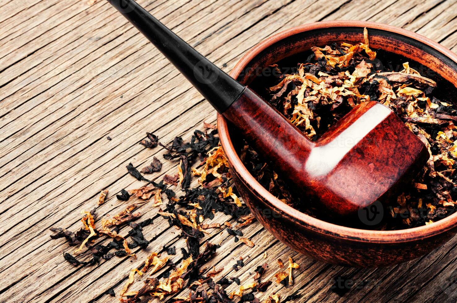 Pipe and tobacco on rustic background photo
