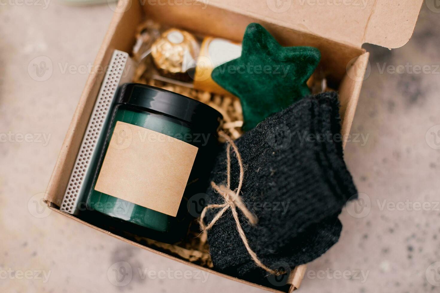 Christmas box with presents - candle in dark jar, chocolate candies, cozy grey socks and festive decoration. Personalized craft box for winter holidays photo