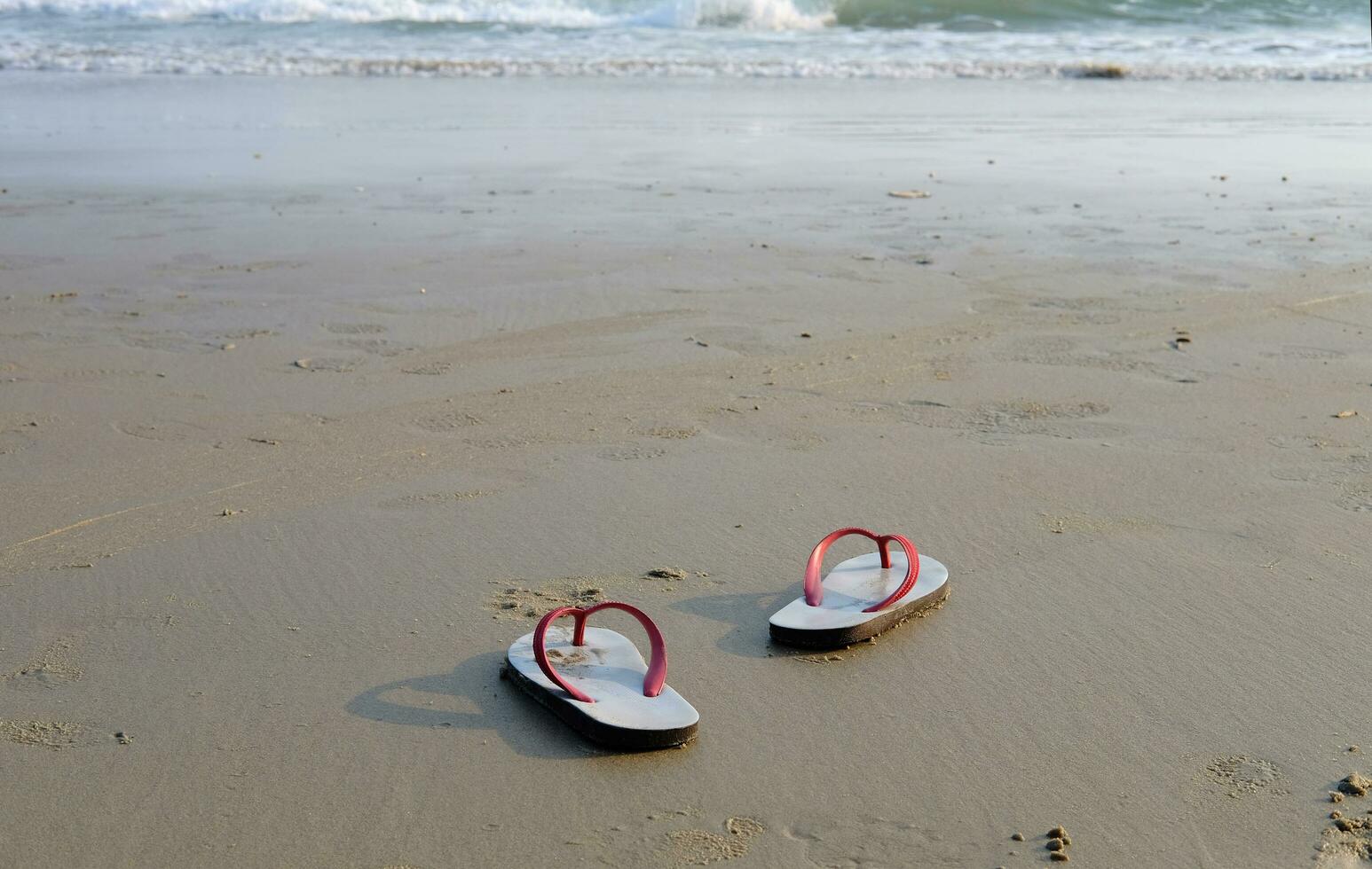 Sandals and shoes footprints on the beach and blue sea. photo