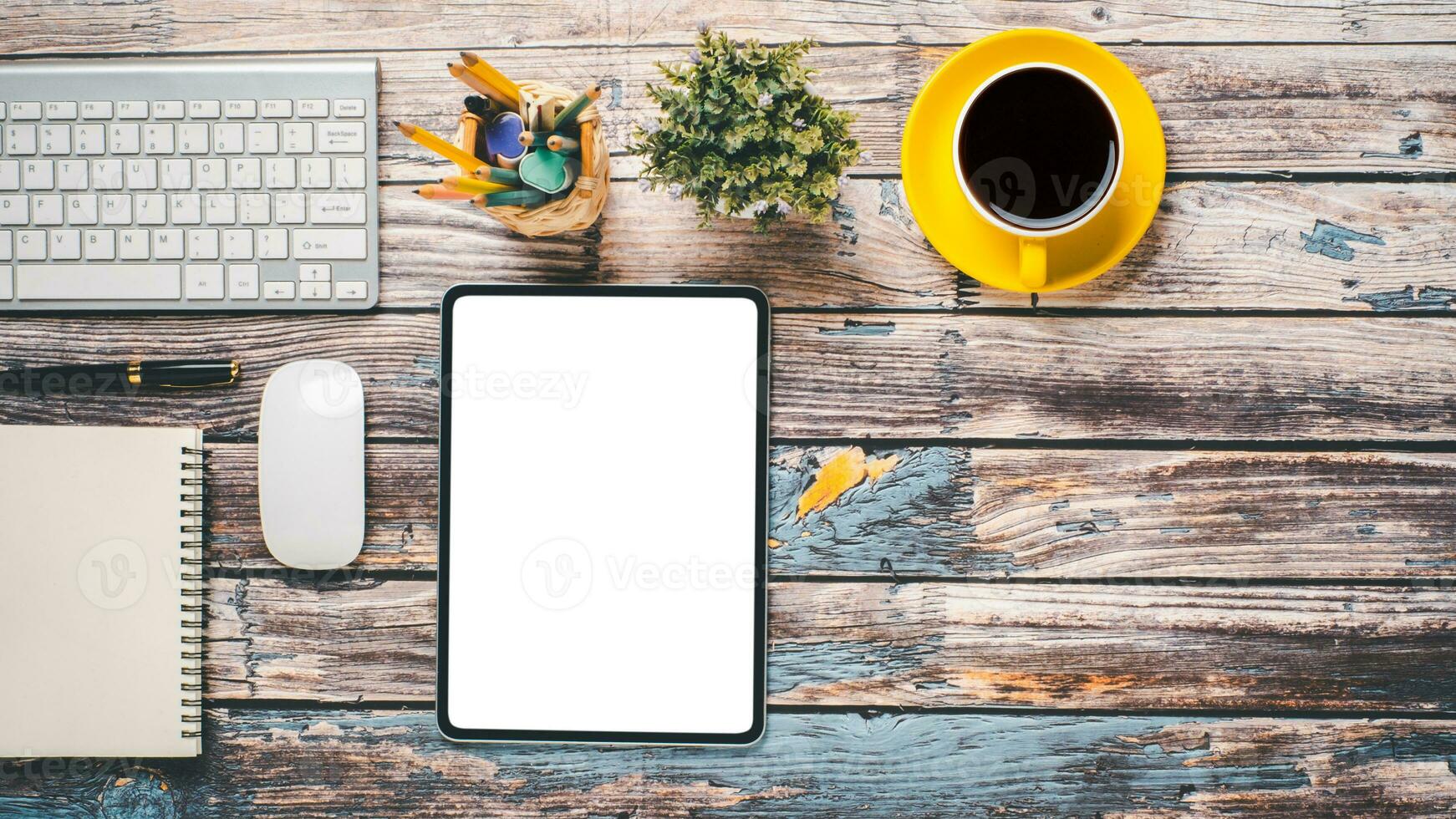 Woodn desk workplace with blank screen tablet, mouse, keyboard, pen, notebook and cup of coffee, Top view flat lay with copy space. photo